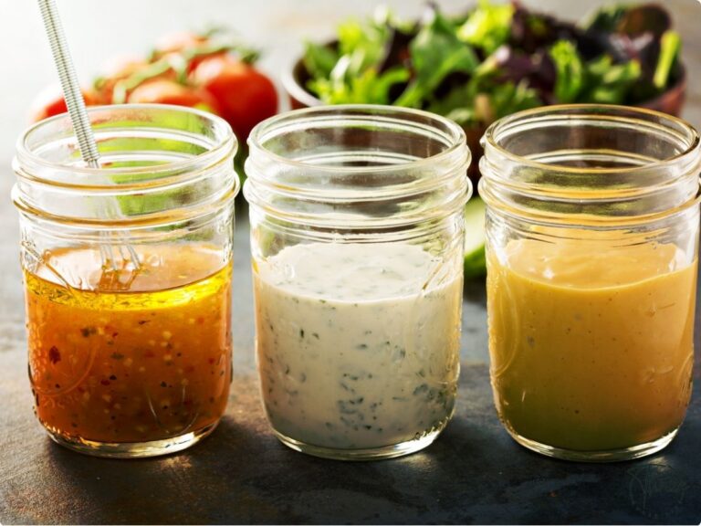 Fresh salad dressings in mason jars with fresh ingredients in the background