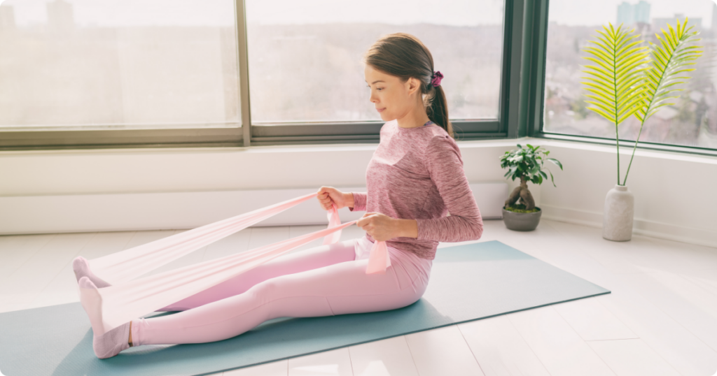 A nurse at home following a resistance band routine on a yoga mat.