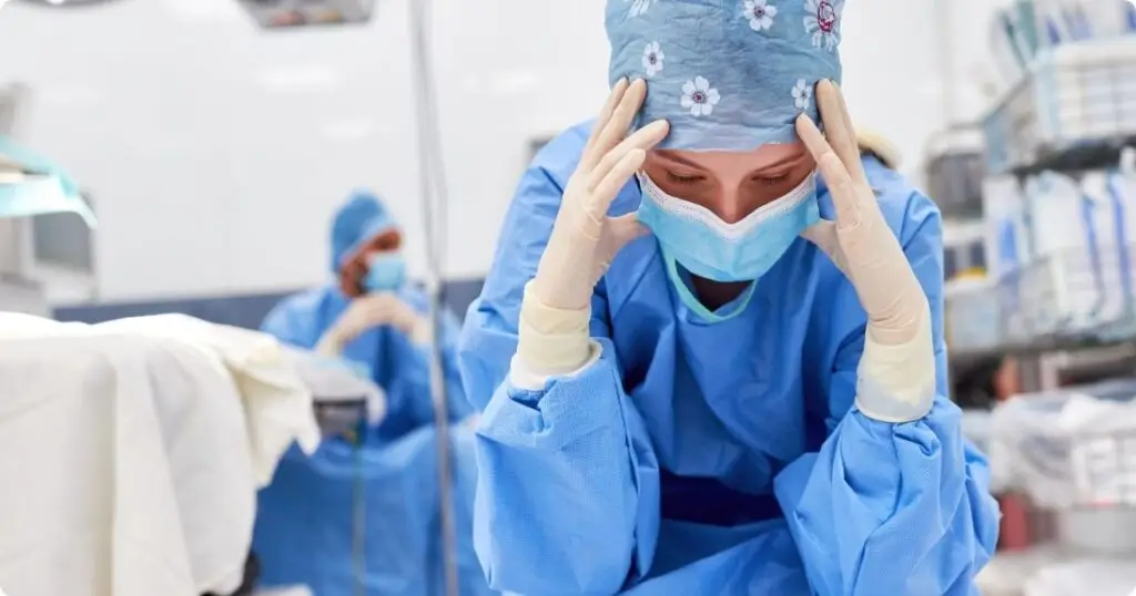 A nurse with eyes downward in dejection showing signs of compassion fatigue.