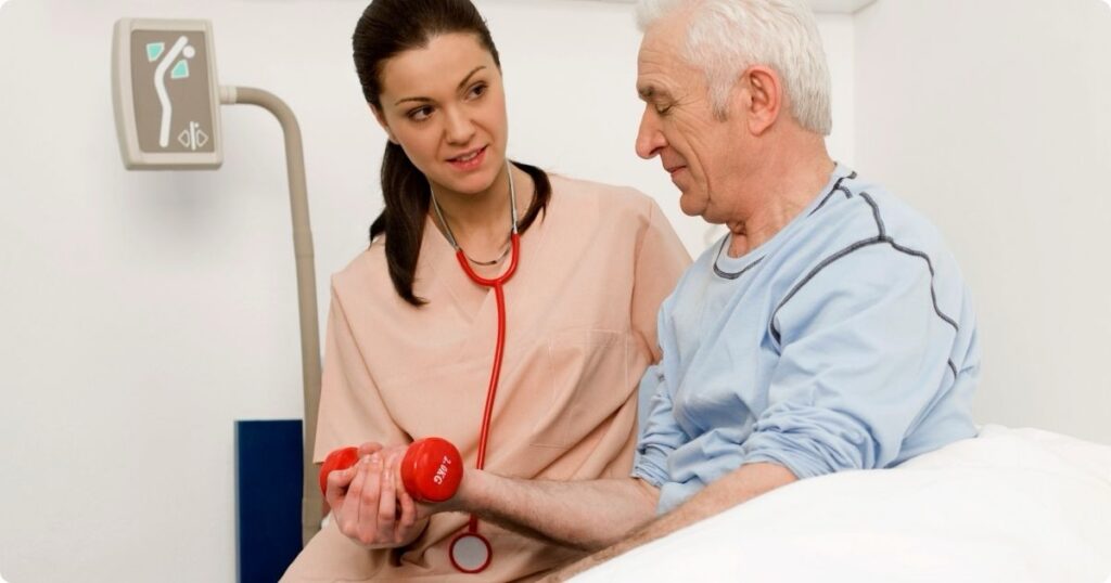 A nurse in scrubs helps an elderly man and woman lift small dumbbells – illustrating strength training for nurses.