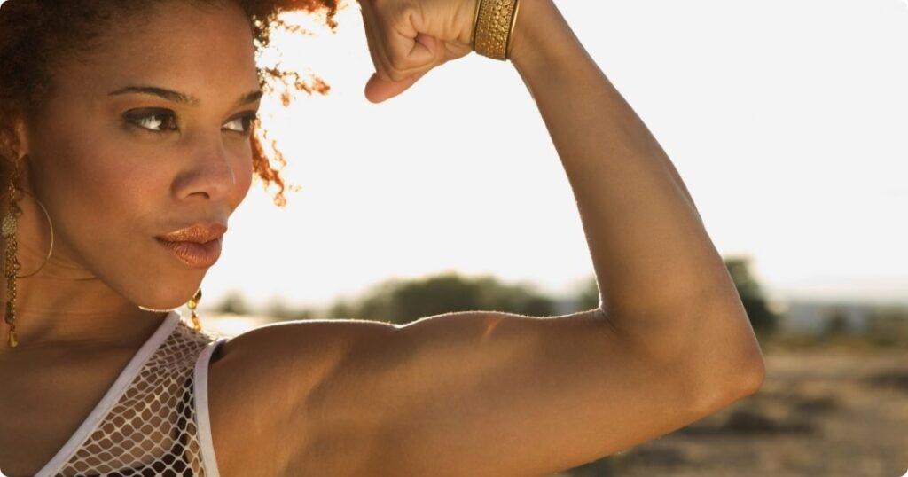 A female healthcare professional flexes her arm – embodying strength training for nurses.